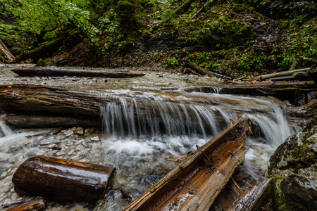 Waterfall from ravine in autumn, long exposure, in mountain river with rocks and tourist trail stairsの写真素材
