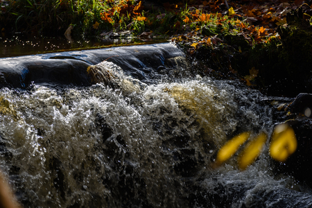 Waterfall from ravine in autumn, long exposure, in mountain river with rocks and tourist trail stairsの写真素材