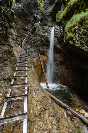 large Waterfall from ravine in autumn, long exposure, in mountain river with rocks and tourist trail stairsの写真素材