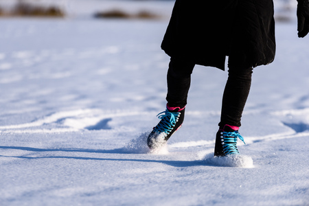 young woman in black coat skating on the frozen lake in snow with modern skates. close up shoot, making tricks freestyleの写真素材