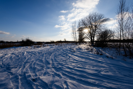 snowy winter road covered in deep snow with car tire tracks going in random directionsの写真素材