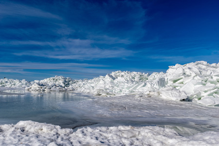 frozen lake covered with stack of ice floes and blue sky. latvia, winter