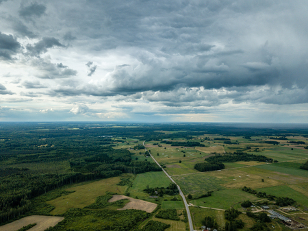 drone image. aerial view of rural area with houses and roads under heavy rain clouds in summer day. latviaの写真素材