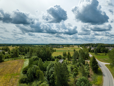 drone image. aerial view of rural area with houses and roads under heavy rain clouds in summer day. latviaの写真素材