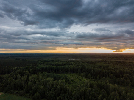 drone image. aerial view of rural area with houses and roads under heavy and dark dramatic rain clouds in summer day. night photo. latviaの写真素材