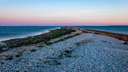 dramatic sunrise over the baltic sea with rocky beach and trees on the shore. long exposure shot....