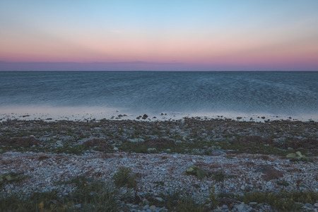 dramatic sunrise over the baltic sea with rocky beach and trees on the shore. long exposure shot. Estonia, Hiiumaa island - vintage retro lookの写真素材