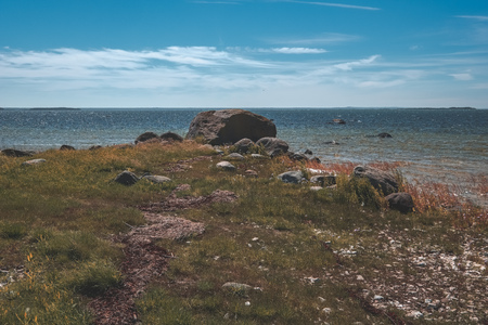 rocky sea beach with wide angle perspective over the sea with sunny sky and waves - vintage retro...
