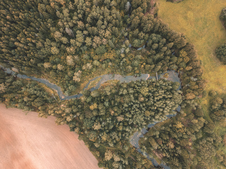 drone image. aerial view of rural area with fields and forests with snake river in woods. latvia,...