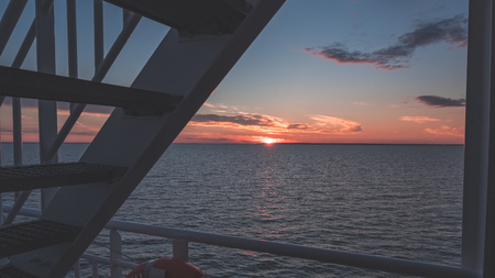 dramatic red sunrise over the baltic sea seen through ships ropes and metal railings - vintage retro lookの写真素材