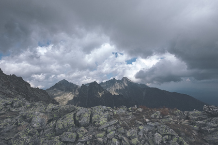 rocky sharp mountain tops in Tatra mountains in Slovakia with clouds and mist from above and rain...