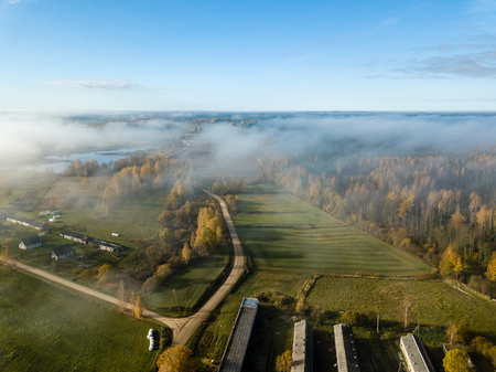 drone image. aerial view of rural area with fields and forests covered in autumn mist. latviaの写真素材