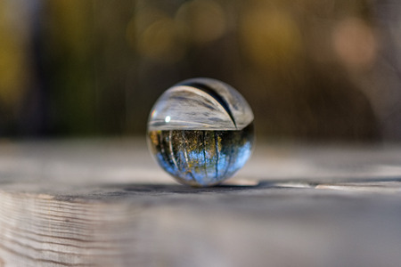 lensball in autumn reflecting nature around it. fall colors hold in human handの写真素材