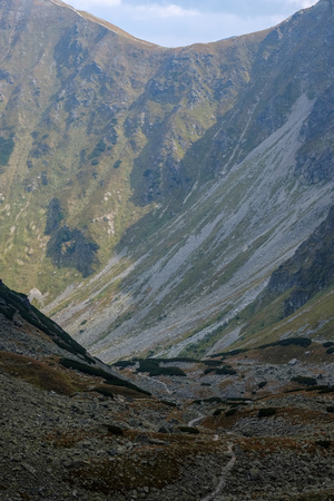 mountain panorama from top of Banikov peak in Slovakian Tatra mountains with rocky landscape and shadows of hikers in bright day with storm clouds approaching in overcast dayの写真素材