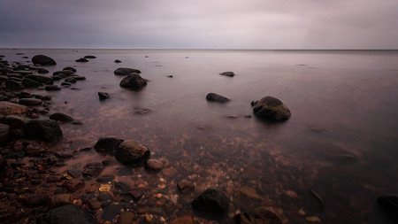 long exposure sea beach with rocks and washed out waves of water. textured abstract image
