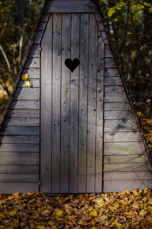 old wooden countryside toilet house with heart shaped hole in the door planksの写真素材