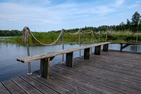 wooden and composite material foot bridge over water in green summer forest surroundings with lakeの写真素材