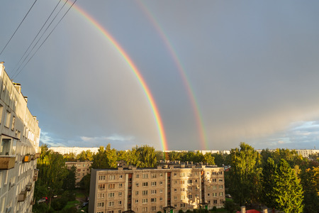 dark storm clouds over city with rainbow and electricity wiresの写真素材