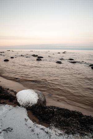 frozen sea side beach panorama in winter with lots of ice and snow in late eveningの写真素材