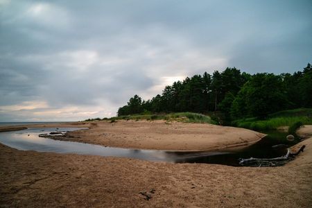 storm clouds forming over clear sea beach with rocks and clear sand. dramatic colorsの写真素材