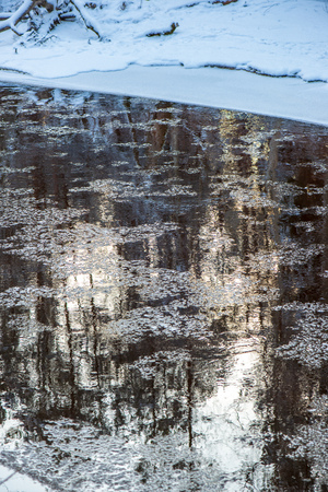 forest river in winter. Amata in Latvia. river with frozen water, ice icicles, snow on rocks and frost on the trees in overcast day.の写真素材