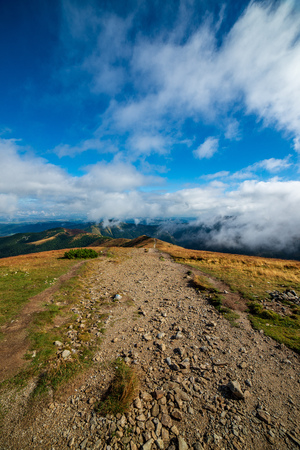 walking above clouds in slovakian Tatra mountains. marked tourist trails with rocks in misty autumn...