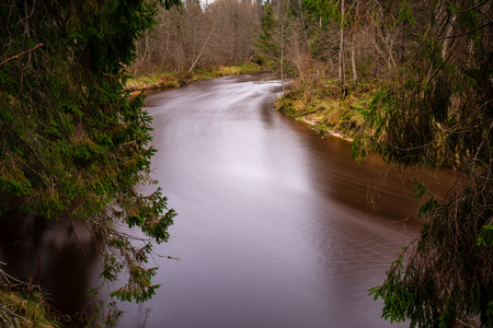 forest river in autumn, with dark brown water and sandstone cliffsの写真素材