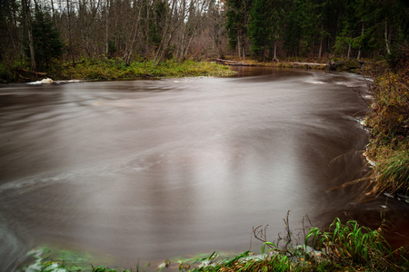 forest river in autumn, with dark brown water and sandstone cliffs