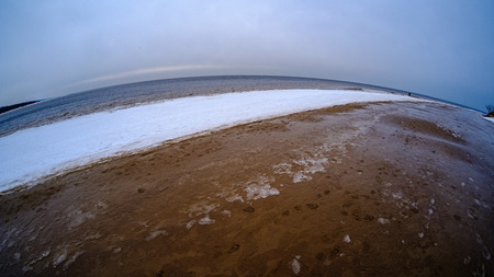 frozen ice blocks on sea beach in winter with sand and snow in overcast day