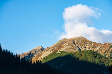 slovakian Tatra mountain high peaks on the blue sky background with broken clouds and sun in summer day. tourist trails for hikingの写真素材
