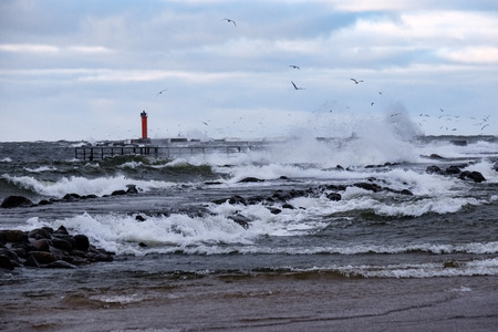 moderate storm in baltic sea near lighthouse in winter with high wavesの写真素材
