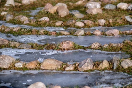 rock ornaments in meadow with frozen water. sunny winter dayの写真素材