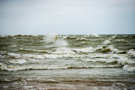 storm weather on the beach by rocky sea shore in latvia. sunset on the rocks with high wavesの写真素材
