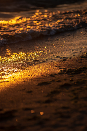 colorful sunset over calm sea beach with dark blue water and dramatic contrasty clouds. rocks in waterの写真素材