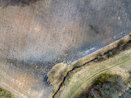 aerial view of small country river bed wavy in spring time in countryside with dry grass and some bushes. fields textureの写真素材