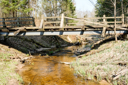 bridge over small forest river, sunny spring dayの写真素材