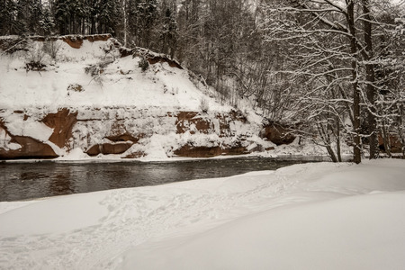 frozen forest river in winter with sandstone cliffsの写真素材