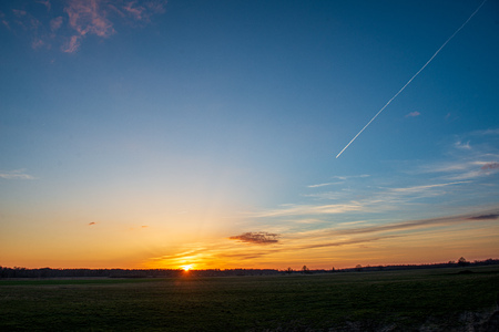 dramatic red sunset colors in the sky above trees and fields. summer sunset in latviaの写真素材