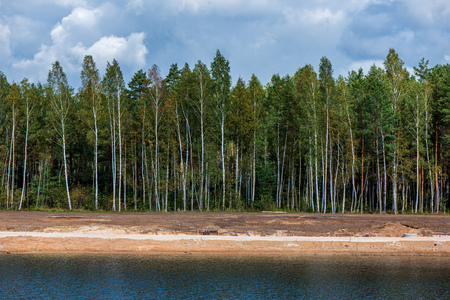 calm countryside lake river with cloud reflections in water and green shores with trees and foliageの写真素材