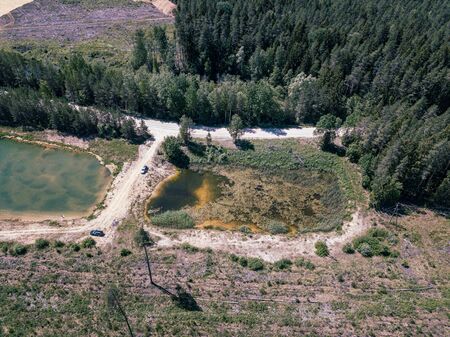 aerial drone view of green lake in forest area with road network in summer