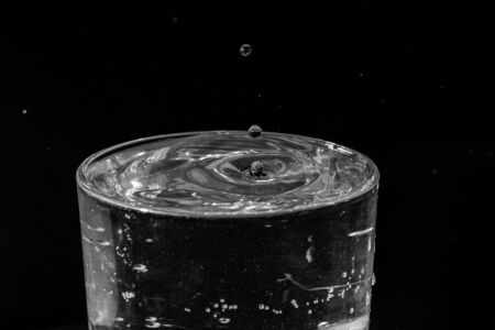 water drops splashing in the glass of water on black backgroundの写真素材