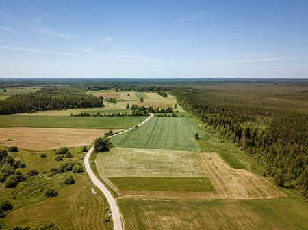 country road in green forest and fields drone aerial image. birds eye viewの写真素材