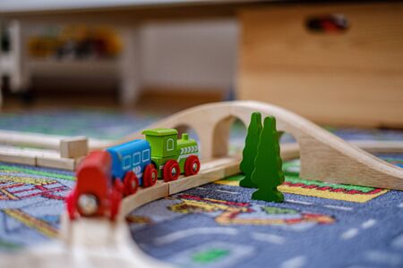 baby hands playing and learning with wooden train set on wooden rails on a carpet in nursery at homeの写真素材