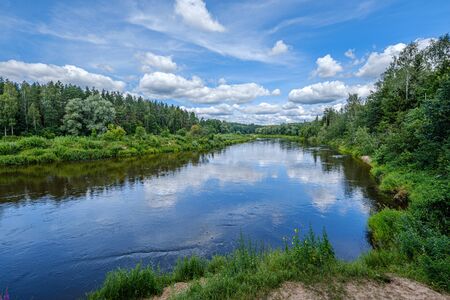 open view to the river of Gauja in Latvia with cloud reflections in water, blue sky summer day