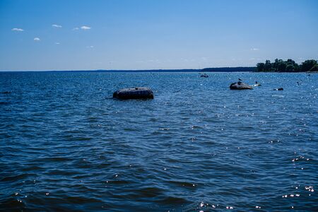 rocky seaside beach with blue water under summer sky and rocks on the shoreの写真素材