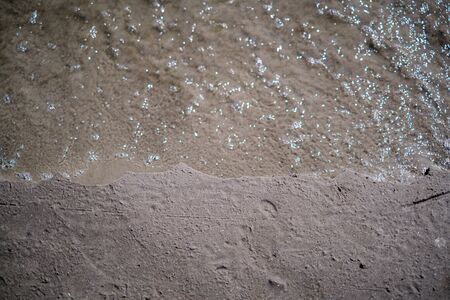 frozen sea beach with sand and first snow in cloudy day in winterの写真素材