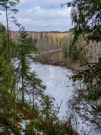 half frozen river in late autumn with trees with no leaves.  partial ice cover over river Gauja in Latviaの写真素材