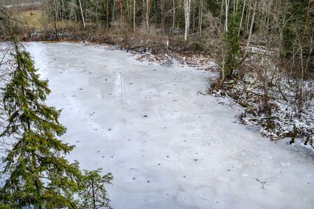 half frozen river in late autumn with trees with no leaves.  partial ice cover over river Gauja in Latviaの写真素材
