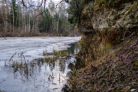 sandstone cliffs in Latvia near river Gauja with ice on water. winter landscapeの写真素材