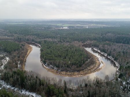 River in winter forest with green trees from above. Aerial drone image of river Gauja in Latvia.の写真素材
